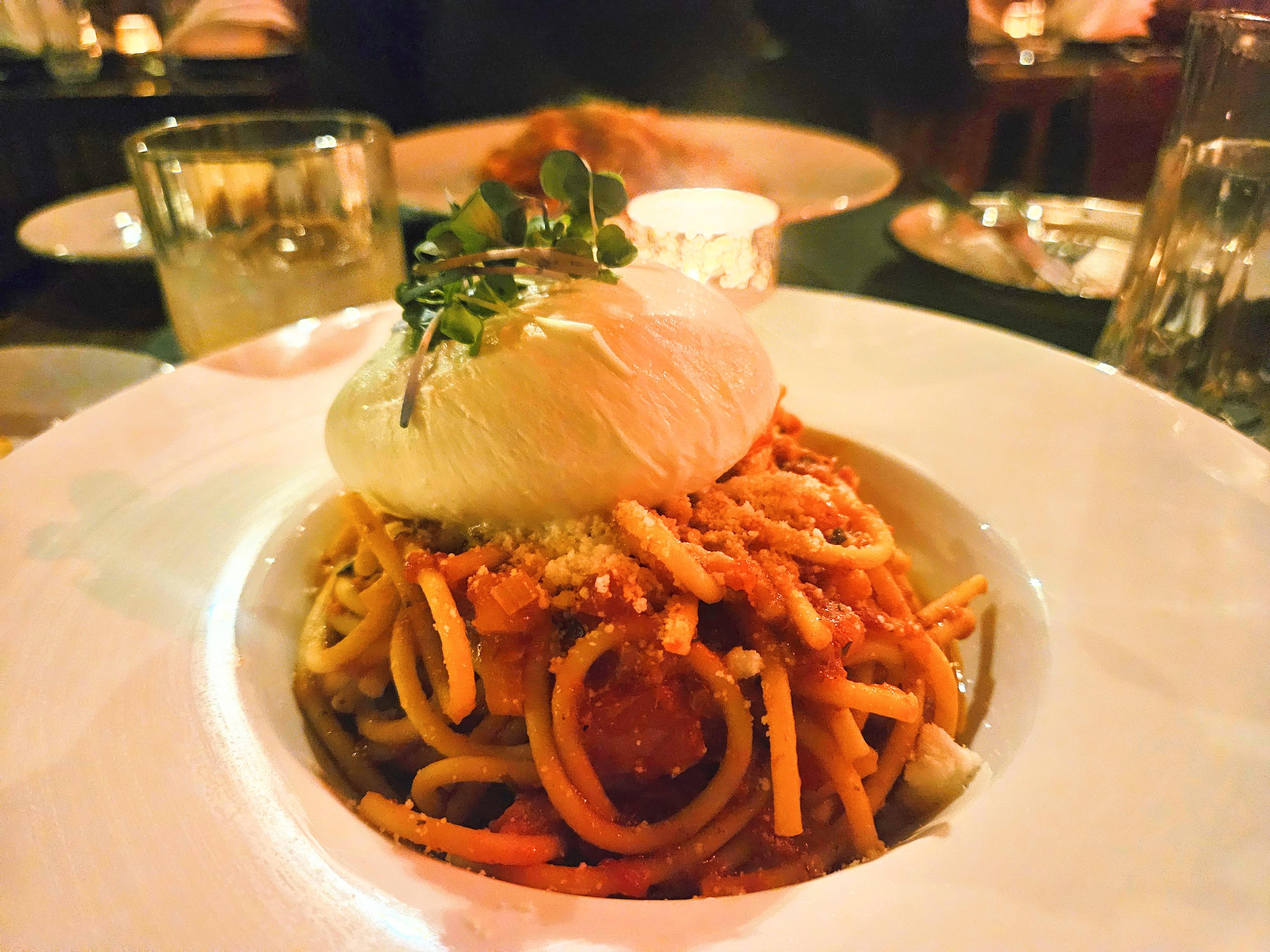 bucatini pasta with burrata cheese on top on a table.