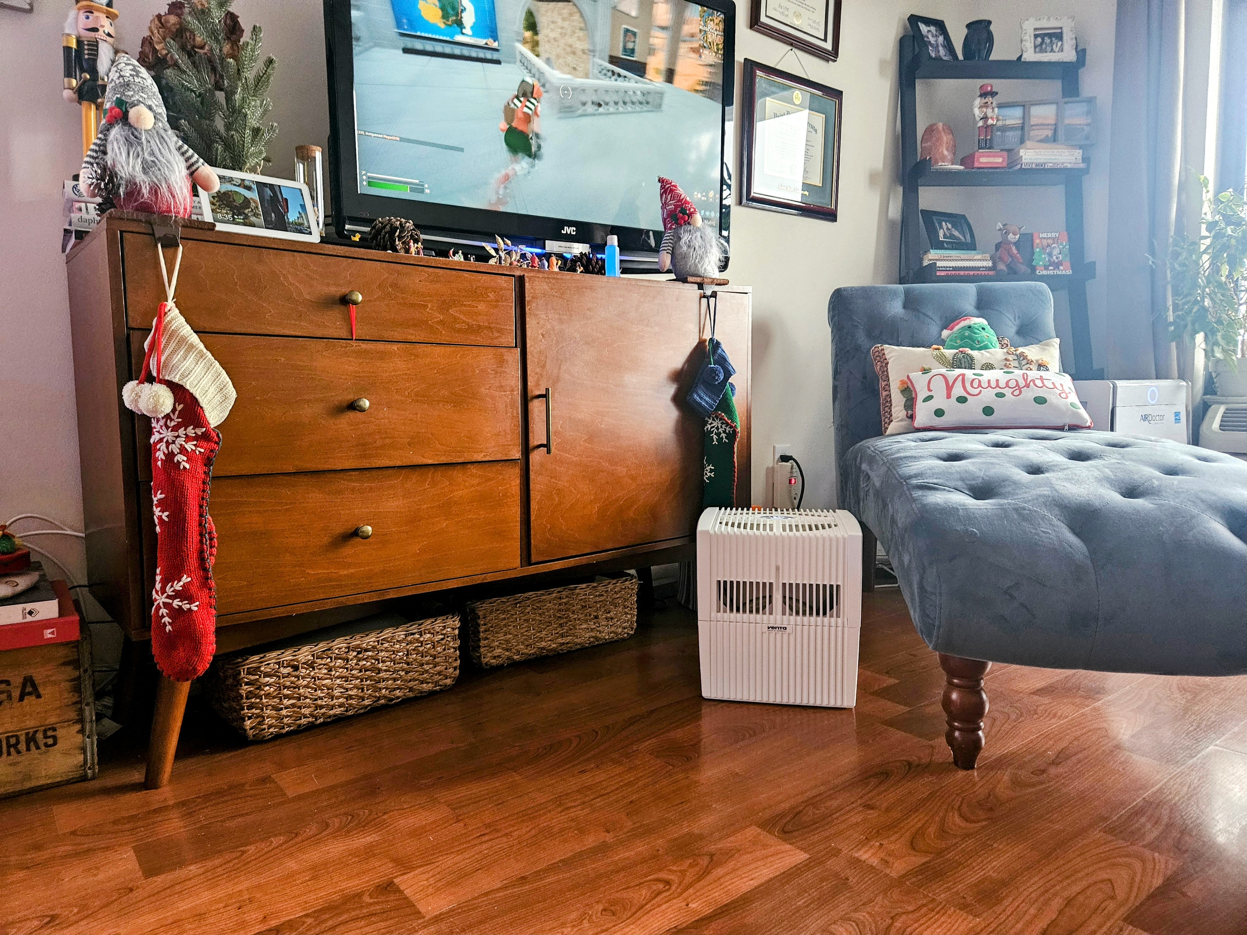 photo of living room with Christmas decorations and a humidifer on the floor in front the stand with a television on it.